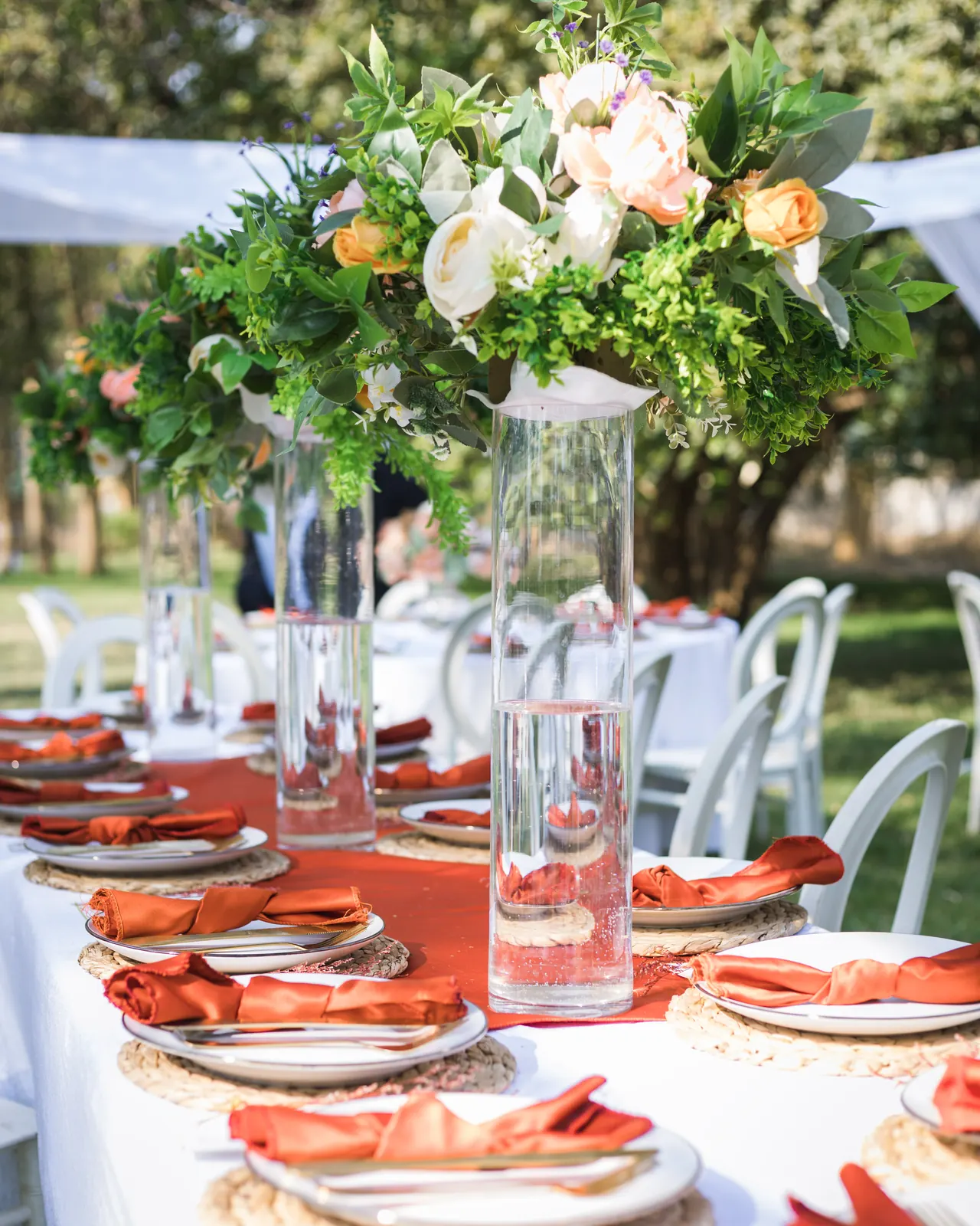 Floral centrepieces arranged along an outdoor wedding reception table